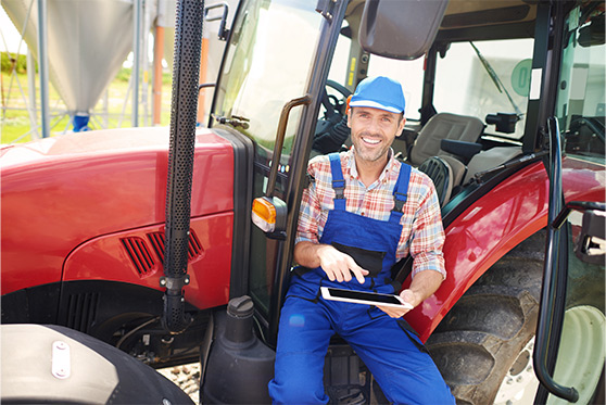 Agriculteur souriant dans un tracteur avec tablette à la main