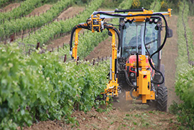 Femme avec calepin devant un tracteur dans un vignoble